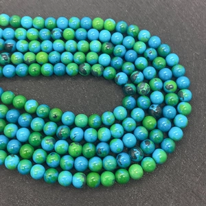 Macro shot of 6-10mm round green Phoenix stone beads with black spots on textured stone