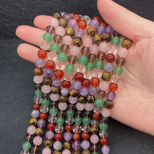 Close-up of natural mixed crystal beads including tiger eye and agate held by hand