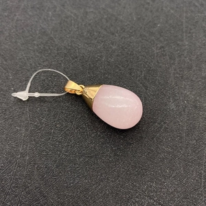 Detail of pink teardrop gemstone pendant with elegant golden metal bail and cap