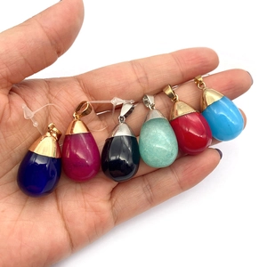 Hand holding set of six teardrop natural stone pendants in vibrant colors with metal clasps