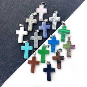Flat lay of multiple natural stone cross pendants with various mineral textures and colors