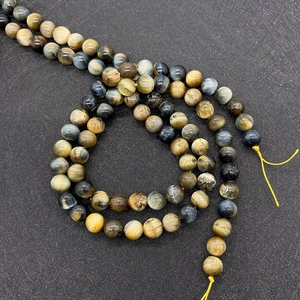 Macro detail of 9mm tiger eye beads with chatoyancy on dark textured board