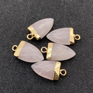 Detalle macro de cinco colgantes de flecha de cuarzo rosa con enganches de metal dorado