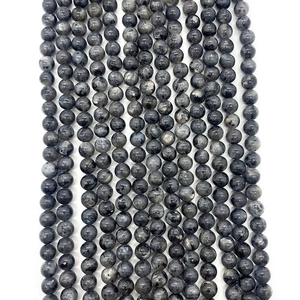 Dettaglio macro di perle tonde in labradorite grigia con texture liscia e lucentezza