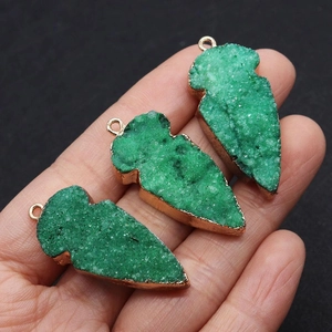 Detailopname van pijlvormige groene kristallen hangers met vergulde metalen randen