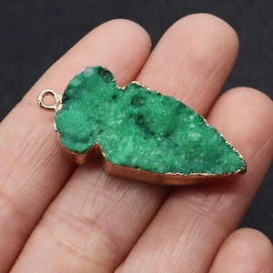 Detailopname van een bladvormige groene druzy kwarts hanger met goudkleurige randafwerking