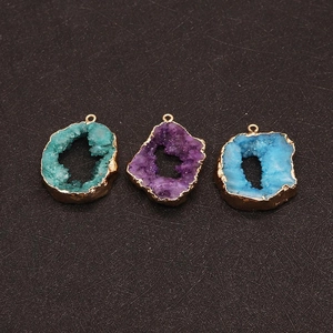 Close-up of three irregular geode pendants with gold edging in green, purple, and blue