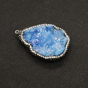 Gros plan du pendentif goutte en agate drusy bleue avec bordure de strass brillants