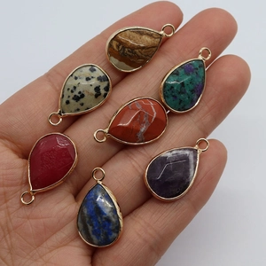 Mixed teardrop natural stone pendants with gold metal edge displayed in hand