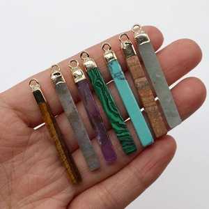 Close-up of rectangular natural stone pendants with gold metal bails held by hand