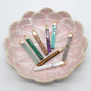Mix of rectangular natural stone pendants like malachite and tiger eye in a pink tray