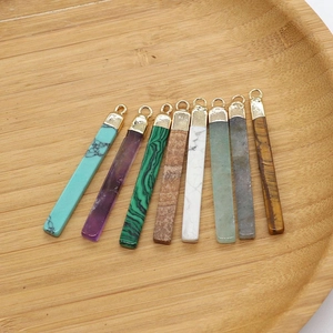 Detail view of various rectangular natural stone pendants with gold-plated metal bails