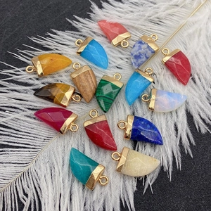 Chili-shaped natural stone pendants with gold caps displayed on a decorative black background