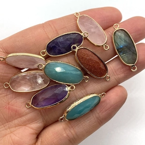 Oval amethyst and amazonite double-loop connectors held in hand for size visualization