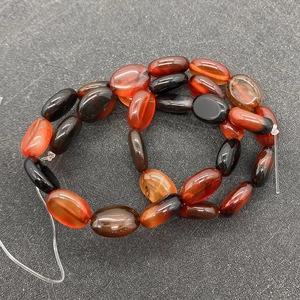 Détail de perles d'agate ovale rouge avec texture marbrée naturelle pour bijoux DIY