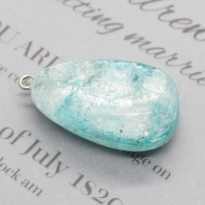Gros plan d'un pendentif en cristal bleu clair en forme de goutte et texture craquelée