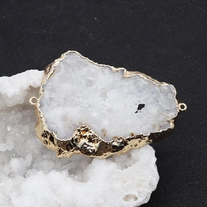 Détail du pendentif en pierre naturelle blanche avec bords dorés et deux anneaux de liaison