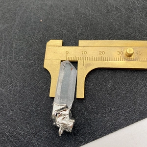 Macro detail showing a clear white quartz pendant measured at 7mm with a golden caliper