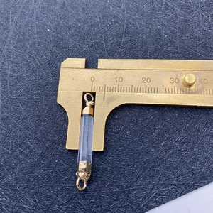 Macro shot of clear crystal connector pendant with gold caps measured by calipers