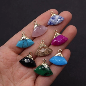 Macro detail of eight colorful gemstone pendants with golden clasps on a hand palm