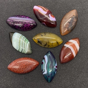 Macro detail of eight colorful marquise-shaped dragon vein agate cabochons for DIY jewelry