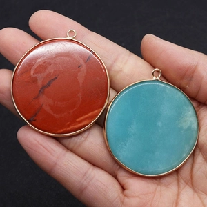 Vue macro de pendentifs circulaires en pierre naturelle avec bordure dorée en main