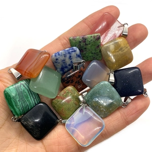 Colgantes cuadrados de piedras naturales con cierres plateados sostenidos en la mano