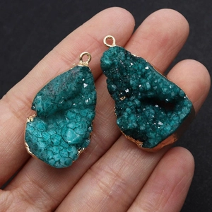 Gros plan d'un pendentif goutte en géode de druzy verte naturelle avec bordure dorée