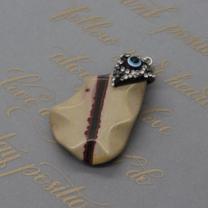 Macro shot of striped natural stone Evil Eye pendant with rhinestone detail and metal clasp