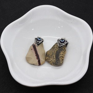 Detail of natural stone pendants featuring evil eye design and diamond-encrusted accents