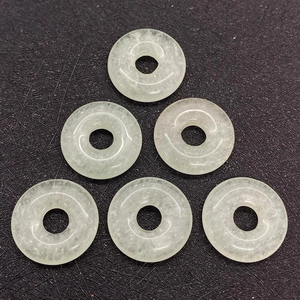 Macro detail of six polished natural green stone donut pendants on a black background