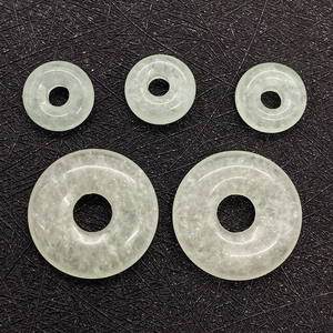 Macro view of five light green natural aventurine stone donut pendants on black fabric