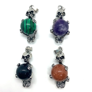 Detailed set of four skull pendants holding round opal and malachite natural stones