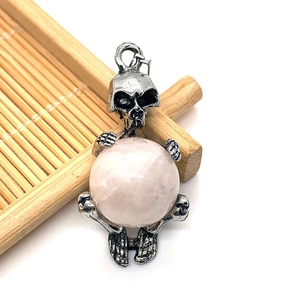 Macro detail of gothic skull pendant holding a large round pink crystal stone