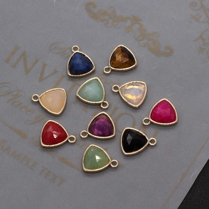 Detailed macro of multi-colored faceted triangular gemstone charms with gold metal plating