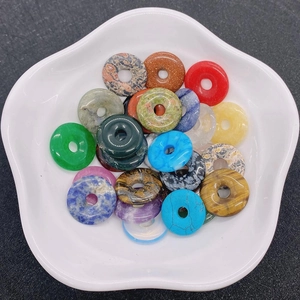 Polierte Donut-Anhänger aus Naturstein wie Tigerauge und Achat in einer weißen Porzellanschale