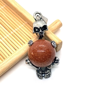 Macro detail of gothic skull pendant with sparkling goldstone sphere on bamboo mat