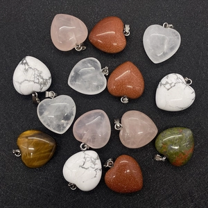 Collectie hartvormige hangers van natuursteen met metalen oogjes op zwarte achtergrond