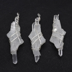 Detailed macro view of raw white crystal pendants with silver wire wrapping on black surface