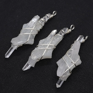 Macro shot of silver wire wrapped natural white crystal pendants on black texture