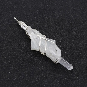 Macro view of clear quartz crystal point pendant with handmade silver wire wrap detail