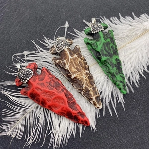 Détail macro de trois pendentifs flèche avec strass incrustés sur un fond noir texturé