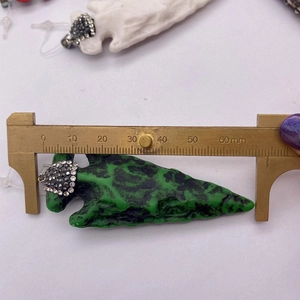 Vue détaillée du pendentif flèche en résine mesuré avec un pied à coulisse en laiton