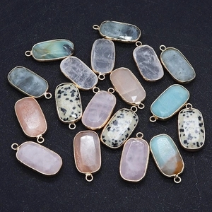 Macro shot of assorted natural gemstone pendants with gold plated edges on dark background