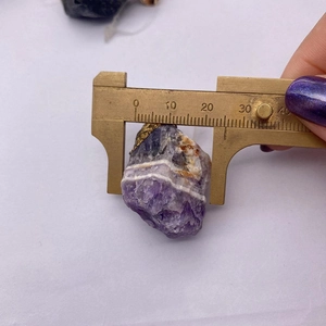 Makroaufnahme eines unregelmäßigen Amethyst-Anhängers mit Messschieber gemessen