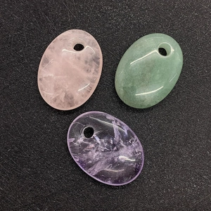 Close-up of oval natural stones in pink, green, and purple with pre-drilled holes