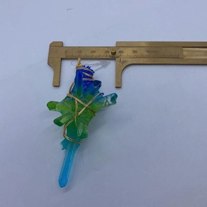 Vista macro che misura la dimensione del ciondolo in cristallo blu-verde con filo d'oro