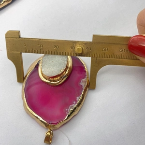 Macro-opname van de roze agaat hanger met gouden randen gemeten met een schuifmaat