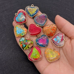 Pendentifs cœur en pierre naturelle dorée présentés en main pour visualiser la taille