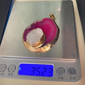 Macro-opname van 35,23g rozerode agaat hanger met gouden plating en witte kristalkluster